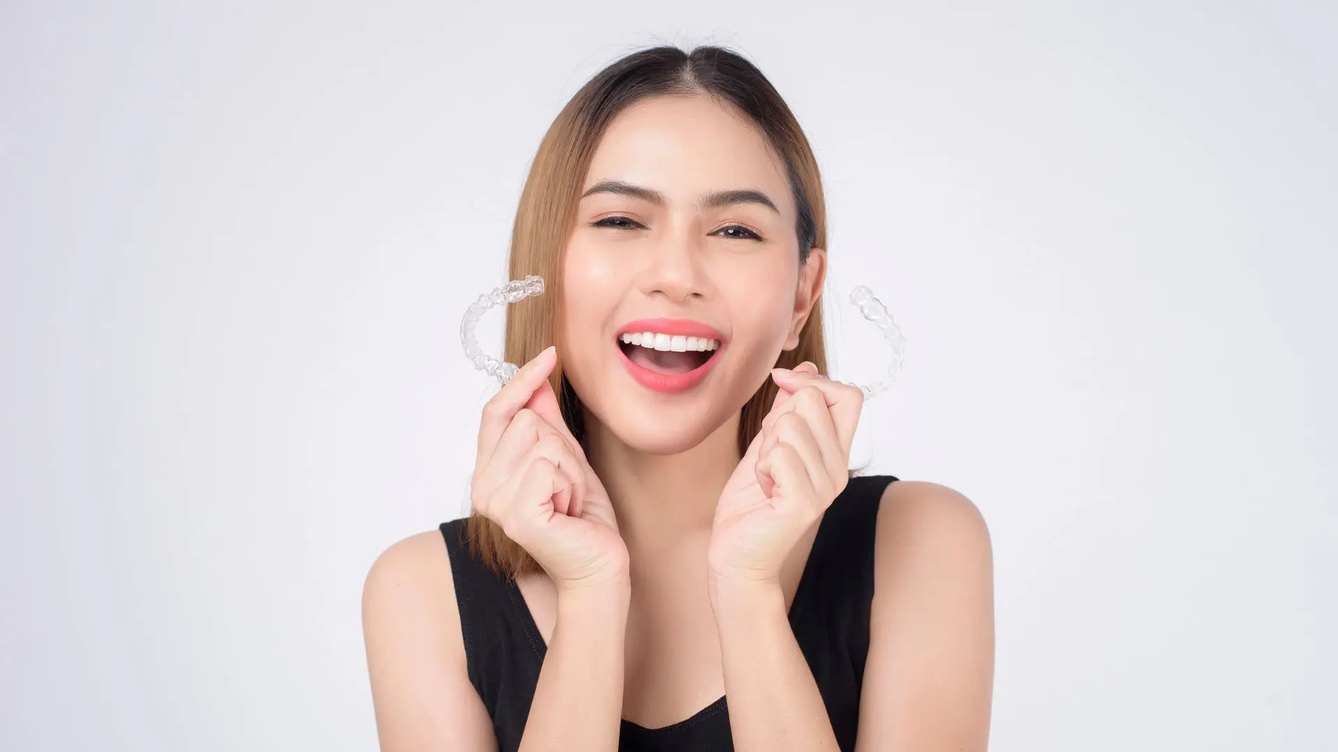 A woman with Invisalign aligners, a comprehensive orthodontic treatment, available at Daia Orthodontics Rochester, MI