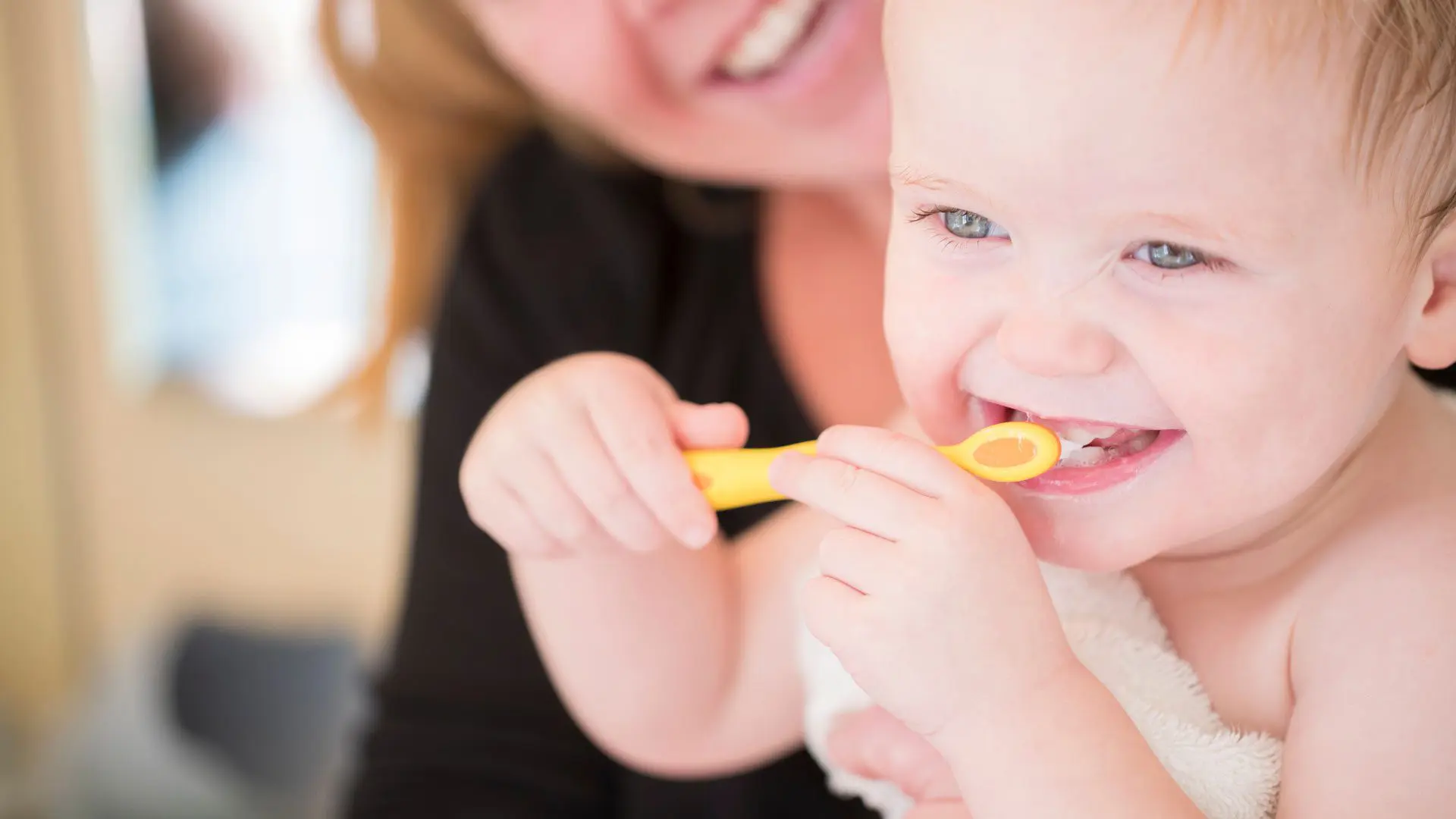 A baby learning how to brush their teeth. Learn more about early oral hygiene habits for kids.