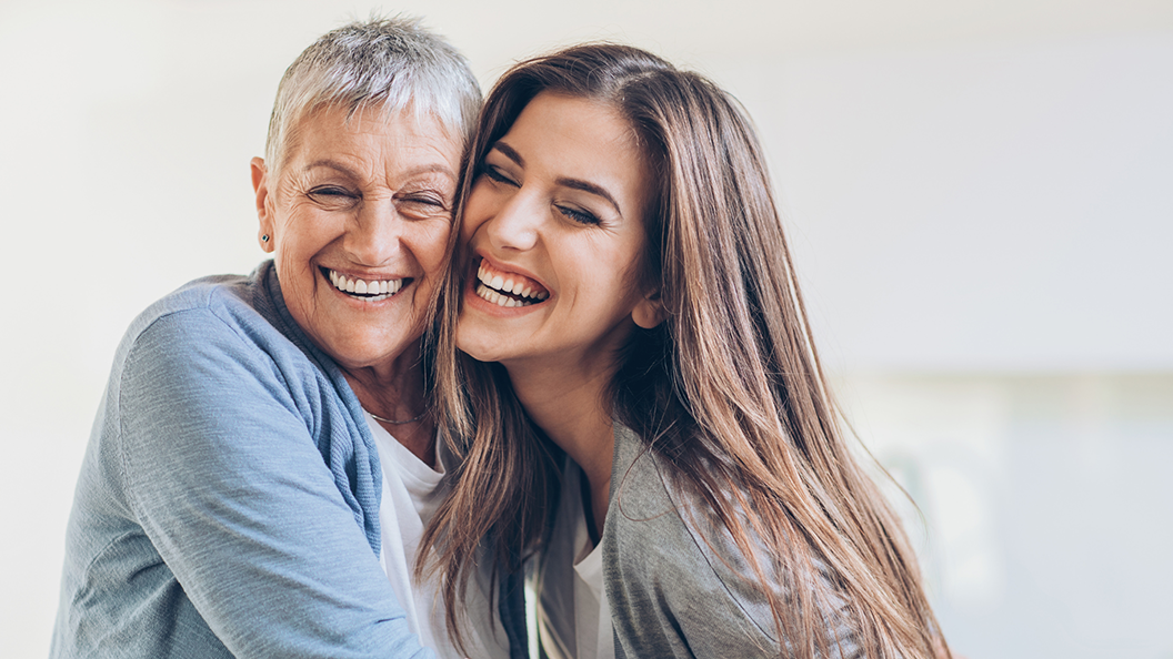 two people sitting closely together and smiling confidently due to adult orthodontic options