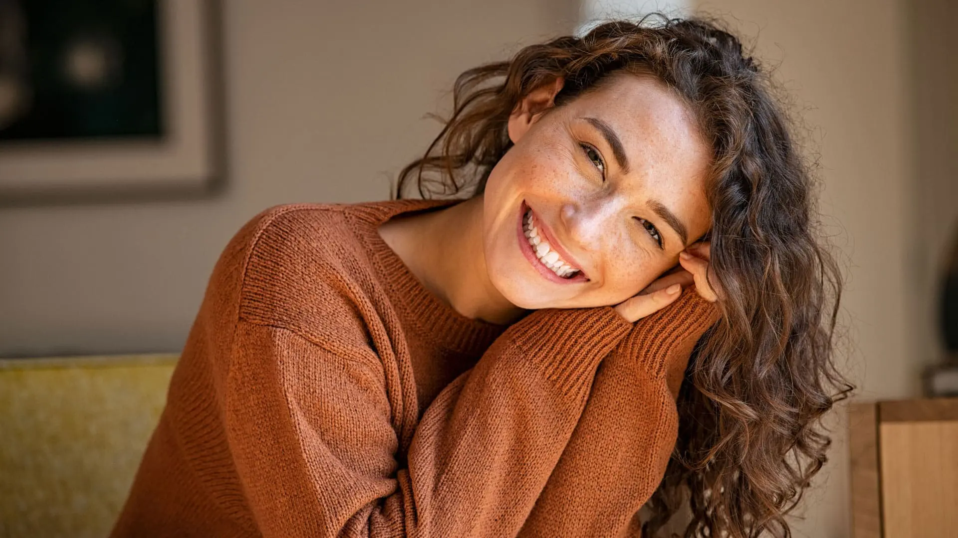 A young woman with long curly brown hair smiling