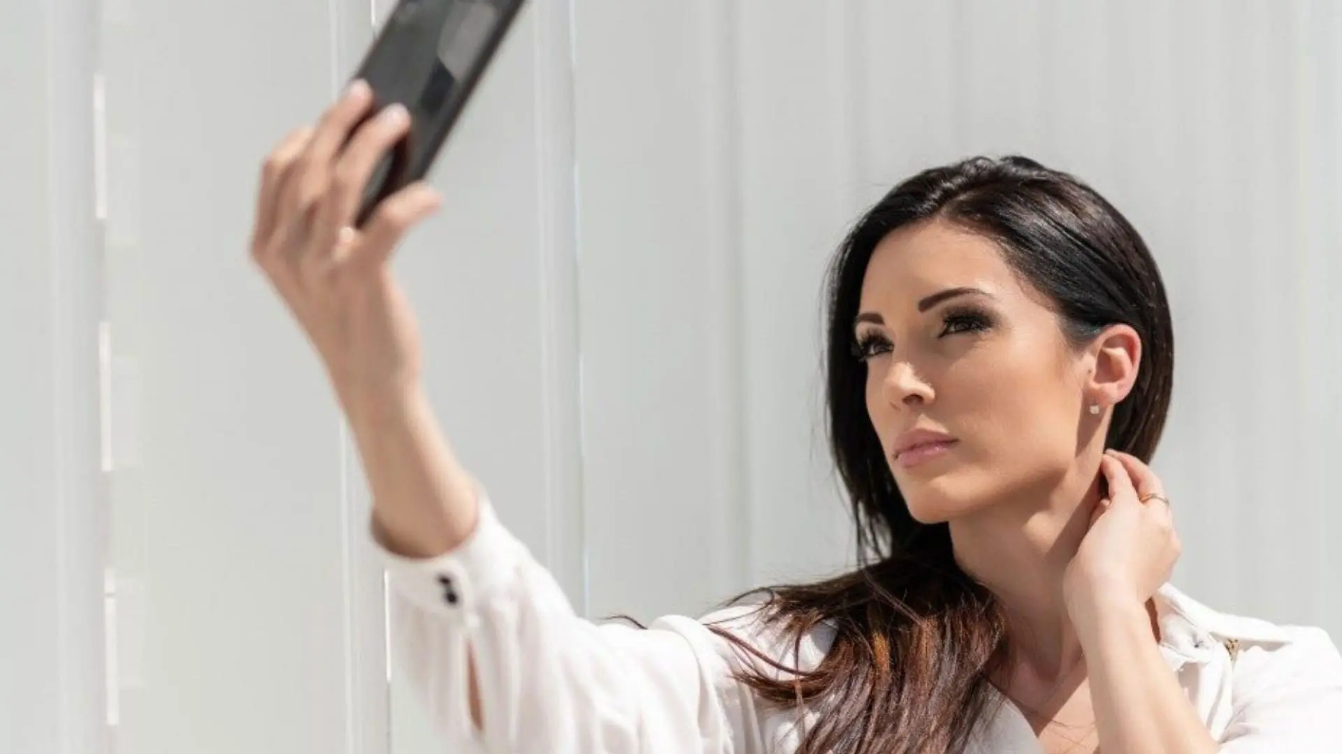 A woman with a slim jaw taking a selfie with a smartphone